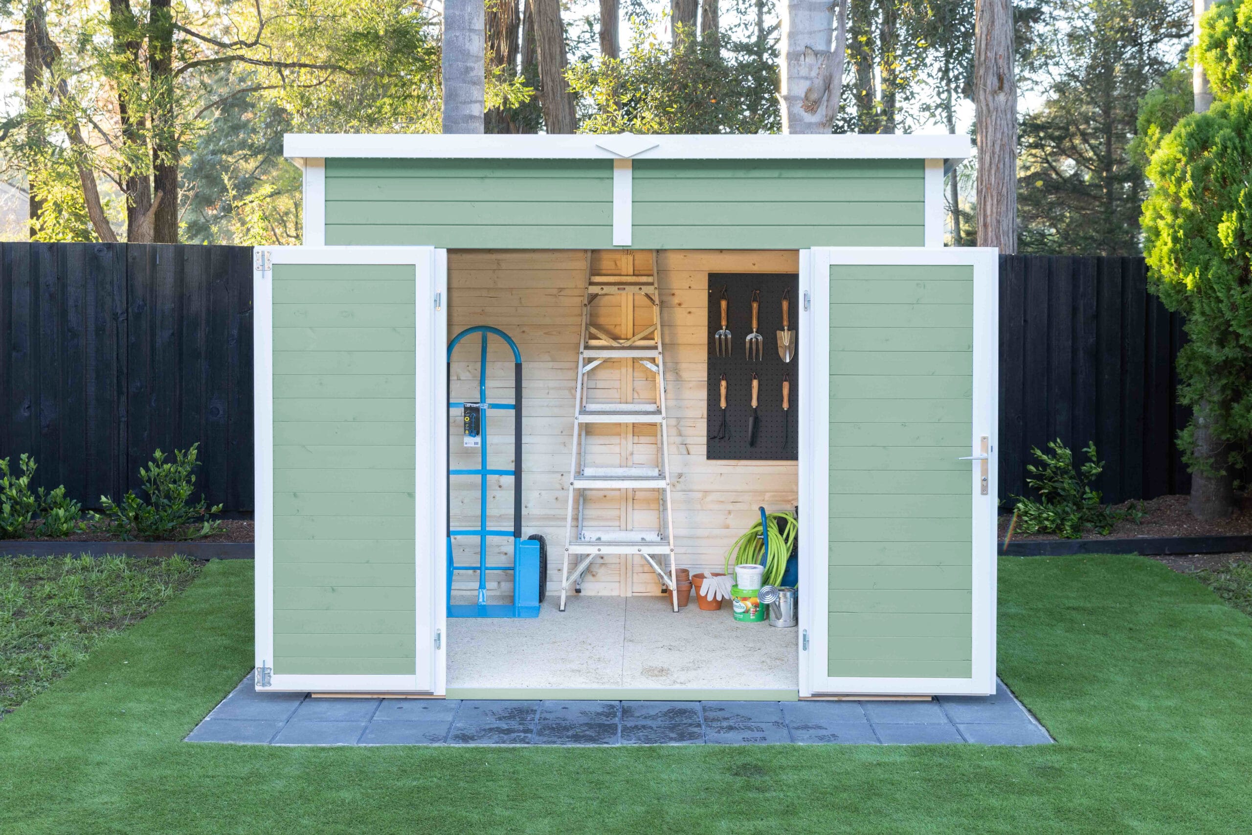 green painted kakadu shed with doors open and trolley and ladder inside